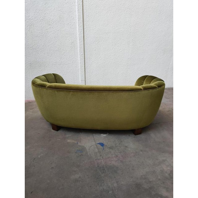 Banana curved sofa with an elegant design and green velvet upholstery, Denmark, 1980s. – Wooden legs. – Tufted finish on...