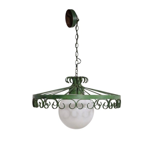Stylish vintage wrought iron and glass hanging fixture having a wrought iron frame which surrounds the glass ball center...