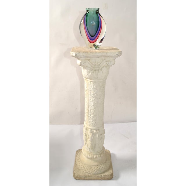 This is a decorative pedestal column designed in a classical Greek or Roman style. The column features a square base with...