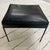 This is a black vinyl and iron ottoman designed by Paul McCobb. Perfect for a footrest, stool or extra seating.