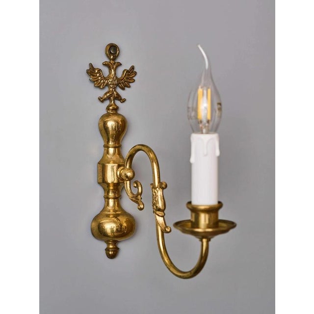 Wall lamp made of cast brass decorated with an eagle and a fish on top. The lamp was made in the mid-20th century. Now the...