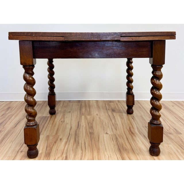 Antique square wood refectory table featuring rich grain and classic barley twist legs. Measures 59.5"L with leaves...