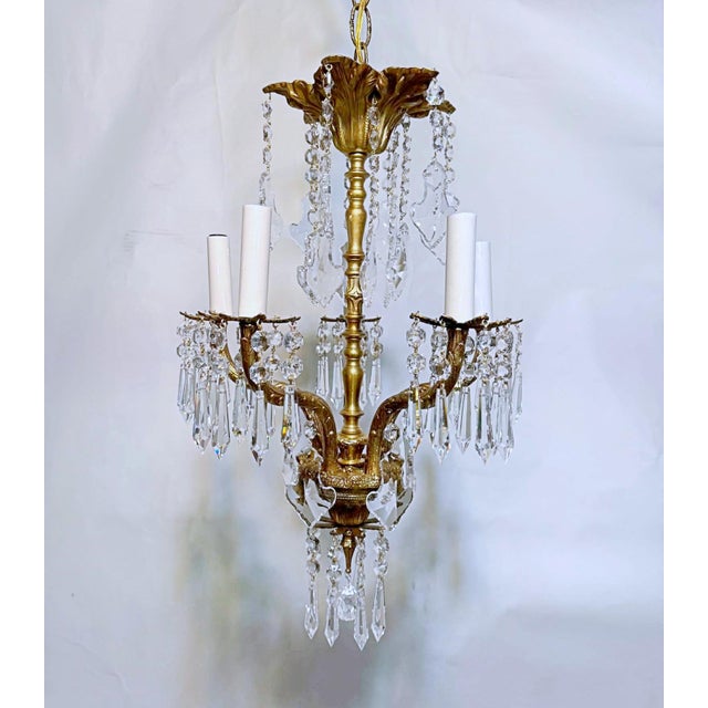 This ornate brass chandelier features a classic five arm candle‑style chandelier arranged around a sculpted central...