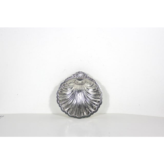 Small vintage footed silverplated clam shell dish or bowl. It has some patina, possible scratches and spots of corrosion....