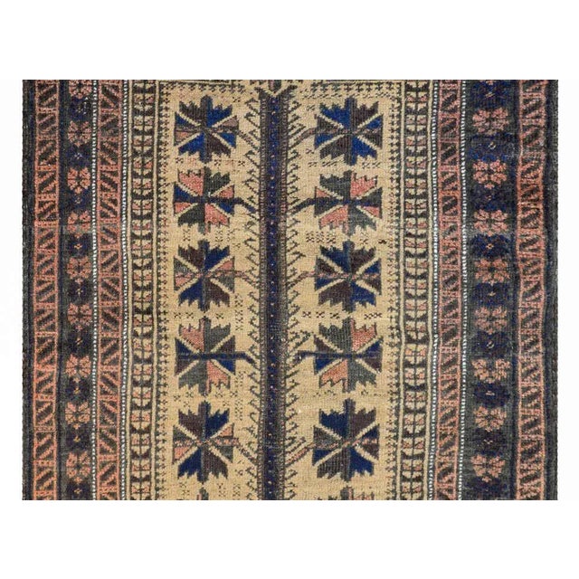A fantastic early 20th century Persian Baluch prayer rug with a large-scale stylized floral pattern woven in brown,...