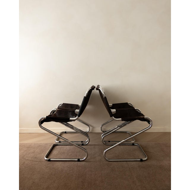 A vintage set of four italian cantilever dining chairs in dark brown cowhide and polished chrome-plated tubular steel,...