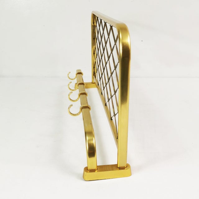 Wall-mounted coat rack, German origin, 1960s. Features four hooks for hanging clothes and a top shelf. Made of brass-...