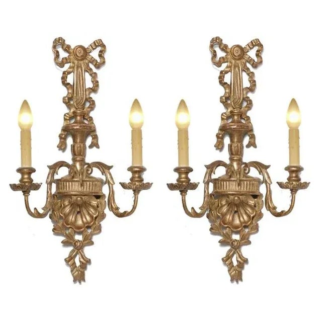 2 light wood carved sconce featuring a shell with ribbon motif in a gold finish. Created in Italy.