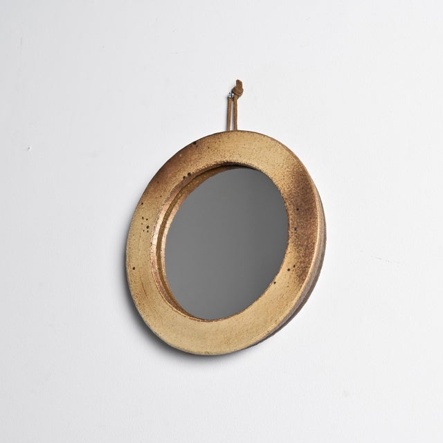 Circular glazed stoneware mirror made in France around 1970. The thick ceramic frame has a matte finish with natural...
