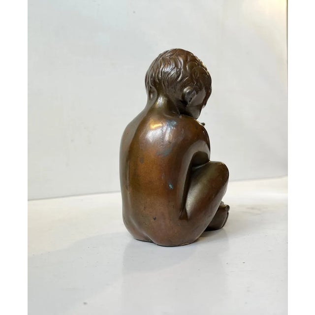 Stylized and mythological small bronze sculpture depicting a baby boy embracing a fish. Designed and studio cast by german...