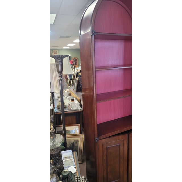 A pair of magnificent tall archtop bookcases. Dating to the 1950s and featuring beautiful salmon color Interiors and of a...