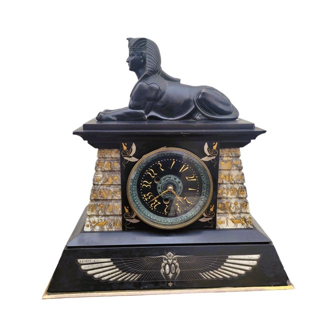 Large clock in the style of Egyptomania, in marble of different colors, decorated with stylized hieroglyphs, falcons and...