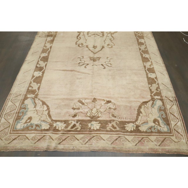 A One-of-a-kind vintage Turkish rug with a blush pink tone encased by an open field medallion motif. Measures: 6'1'' x 12'3".