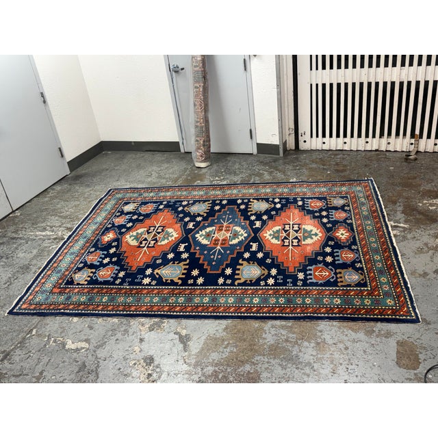 Design Plus Gallery presents a 6ft 6in × 9ft 1in Hand-Knotted Wool Tribal Area Rug. The rug showcases a navy field with...