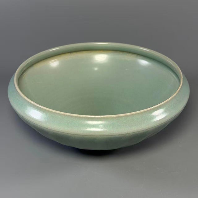 This elegant shallow‑form vessel features classic Longquan celadon glaze with soft mint‑green tone. Subtle carved ribbed...