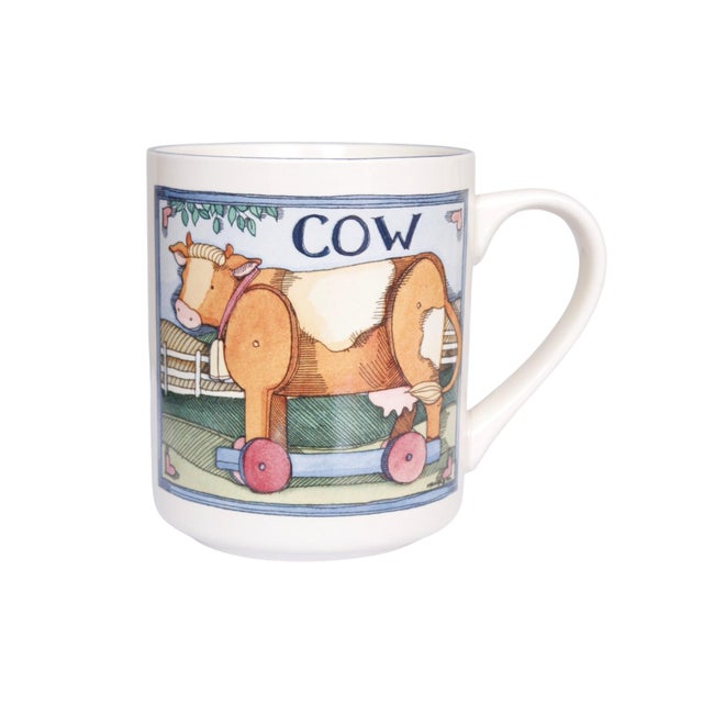 A set of four whimsical ceramic mugs. Four mugs each show a different drawn toy farm animal, labeled on a whimsical...