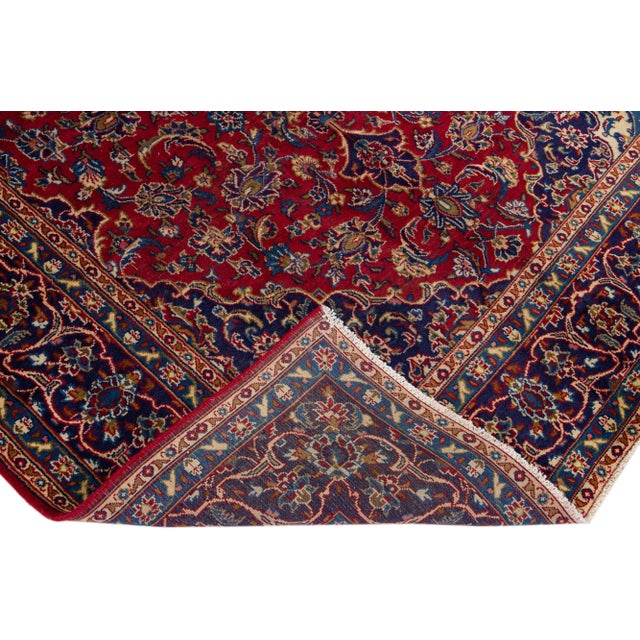 Beautiful Persian Kashan hand-knotted wool rug with a red field. This piece has a blue frame and multicolor accents in an...