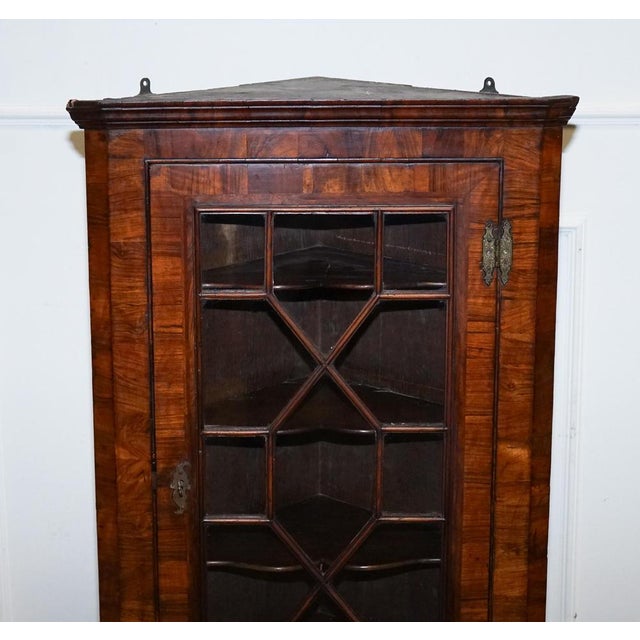 This elegant antique glazed corner cabinet is a fine example of Georgian-style craftsmanship, featuring a beautifully...
