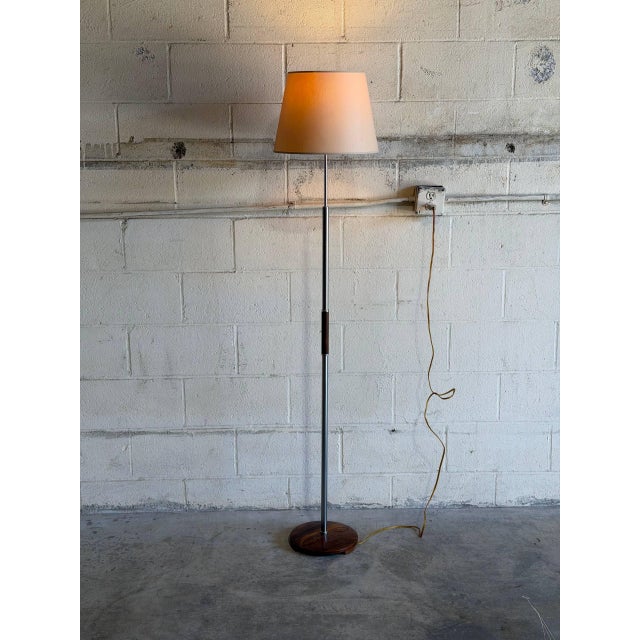 This floor lamp features a sleek metal column paired with rich rosewood accents and a matching circular base. Its refined...