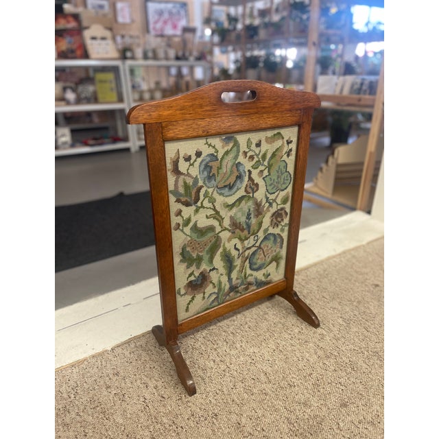 This likely early 20th-century fire screen is a charming example of Arts and Crafts craftsmanship, combining utility with...