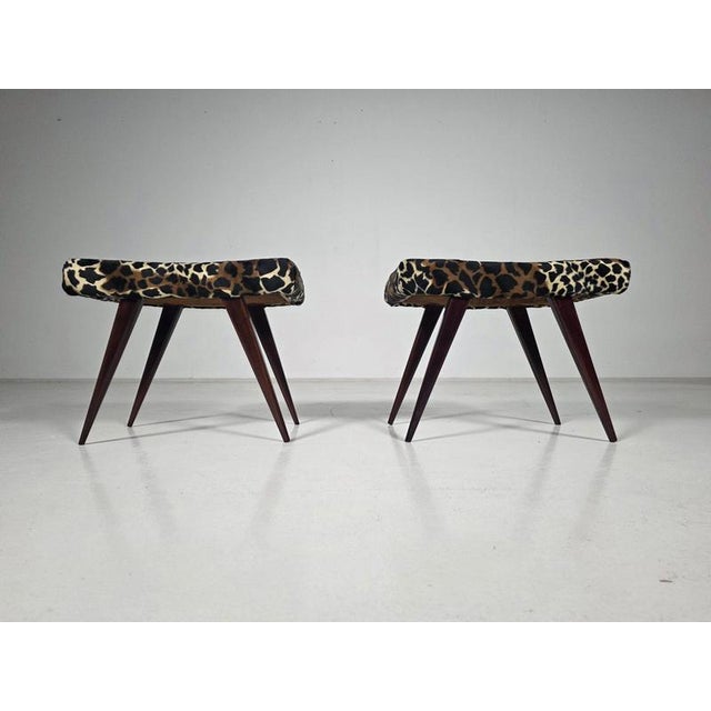 Elegant pair of italian mid-century modern stools or low benches, produced circa 1950s. The stools feature beautifully...