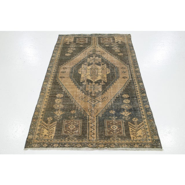 This vintage Persian wool rug has a primary color of tan with gray geometric accents. This rug measures 3'4" x 5'8".