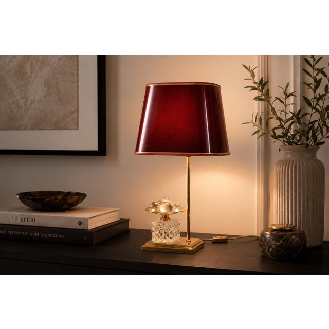 French decorative table lamp dating to the 1970s, with a gold-toned metal base and an offset slender lamp stem. Beside the...