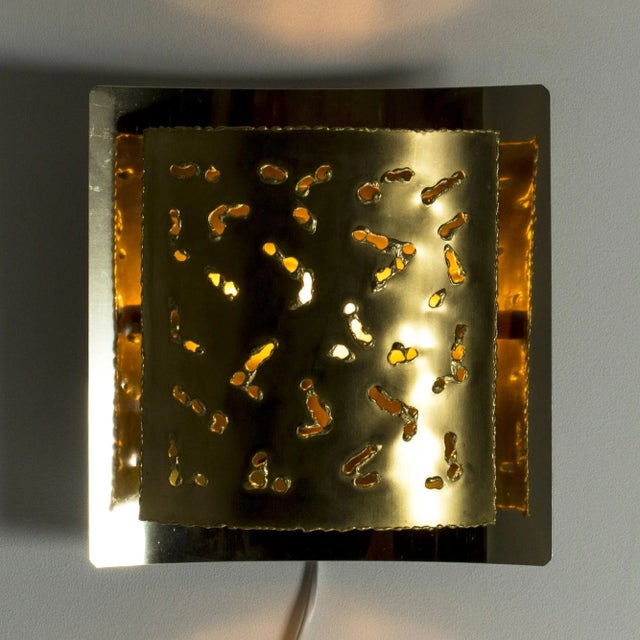 Cool wall lamp from Boréns, made from brass in a brutalist design. The perforated shade creates a burning ember effect...