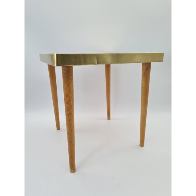 A compact mid-century modern coffee table, made in Europe in the 1960s–1970s. It features a distinctive tabletop made of...