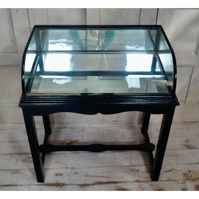 A superb antique oak bow fronted shop display cabinet. Made from ebonised oak, with a bowed glass front, mirrored interior...