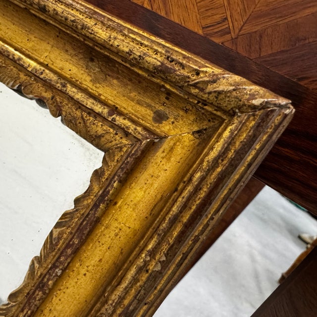 Magnificent antique mirror with a molded and carved wooden frame and a warm, golden patina. On the back, the mirror bears...