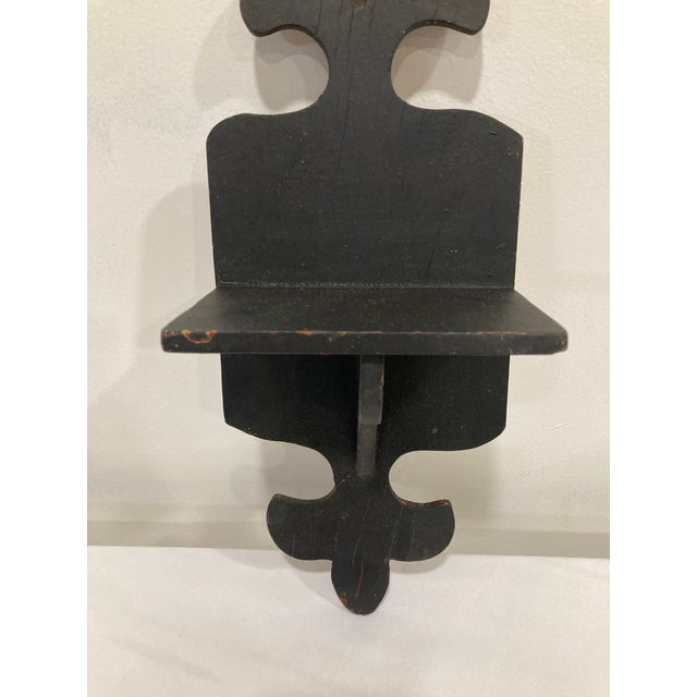 An authentic antique folk art wall shelf crafted from solid wood and finished in black paint. The hand-cut Gothic-inspired...