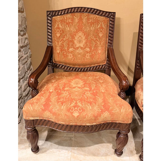 A matching pair of Bernhardt open armchairs with dark walnut-toned wood frames, rope-carved detailing, gracefully curved...