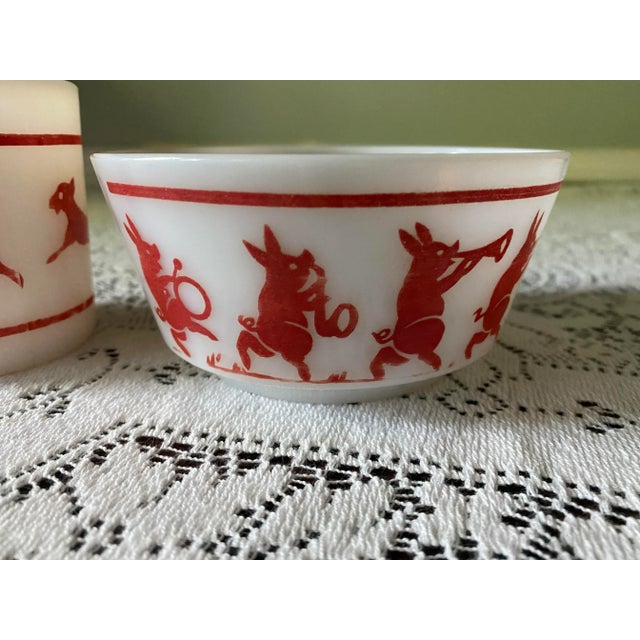 This is a Hazel Atlas child’s cup and bowl in the “musical pigs” pattern. The set is white milk glass with red designs of...