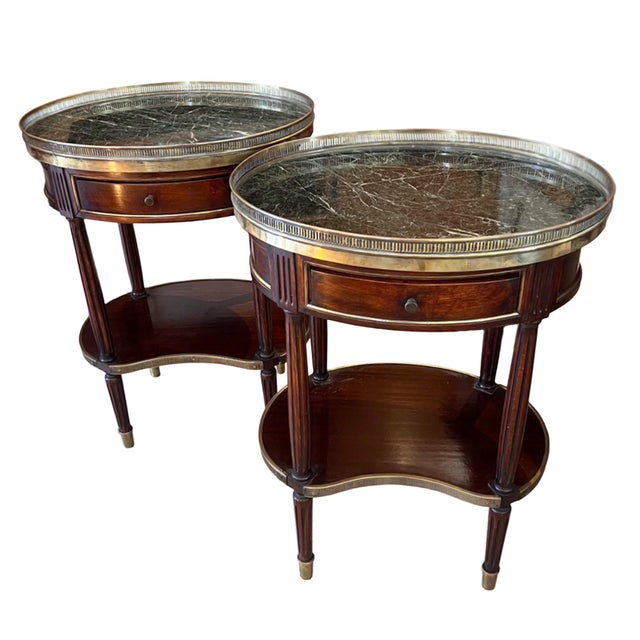 A good pair of oval side tables, with marble tops and brass galleries. Made in France in the 1950s. The lower shelves are...