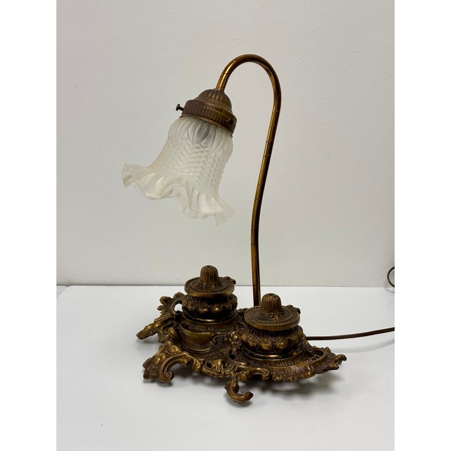 This intricate brass desk lamp featuring two inkwells is likely from the Victorian era. The base in intricately awash with...
