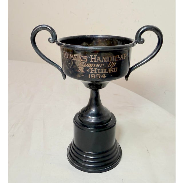 The Vintage 1954 Woman's Handicap runner up silver plate and bakelite trophy is a unique and timeless piece that displays...