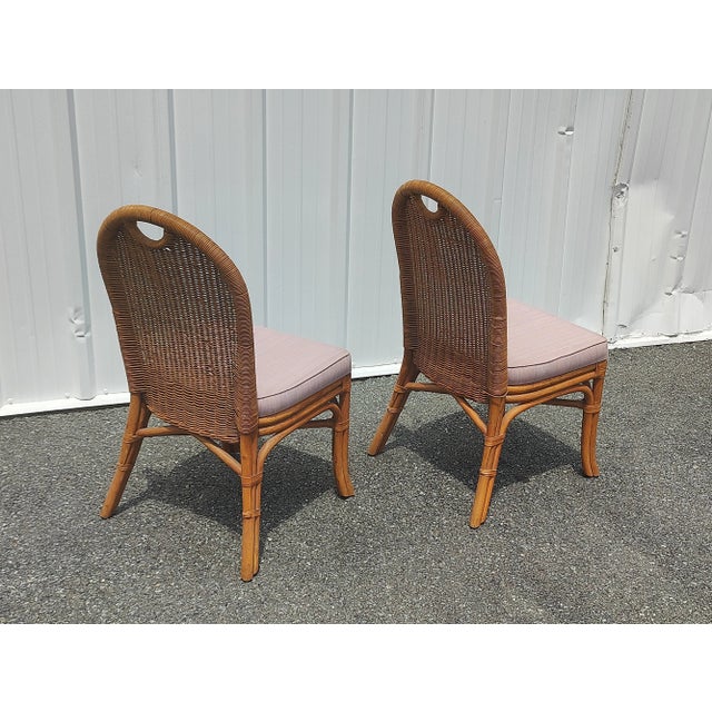 Exceptional vintage boho chic bamboo rattan dining chairs. Each feature a wicker back rest with a baby pink fabric seat...