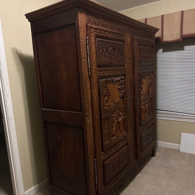 Beautiful, large hand-carved solid wood armoire featuring richly detailed carved panels on both doors. The carvings depict...