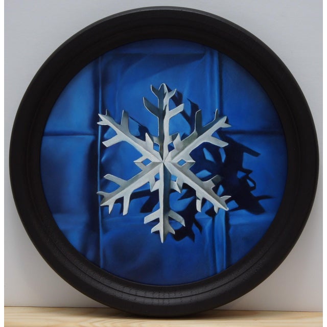 This circular oil painting features a meticulously rendered paper snowflake, its intricate design starkly contrasted...