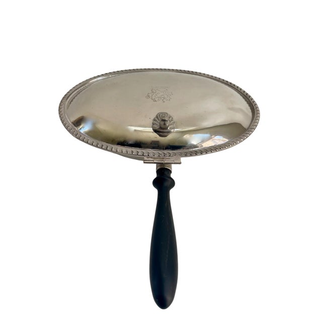 Vintage silver-plate silent butler featuring an oval shape, a hinged lid, and a wooden handle with an embossed lion design...