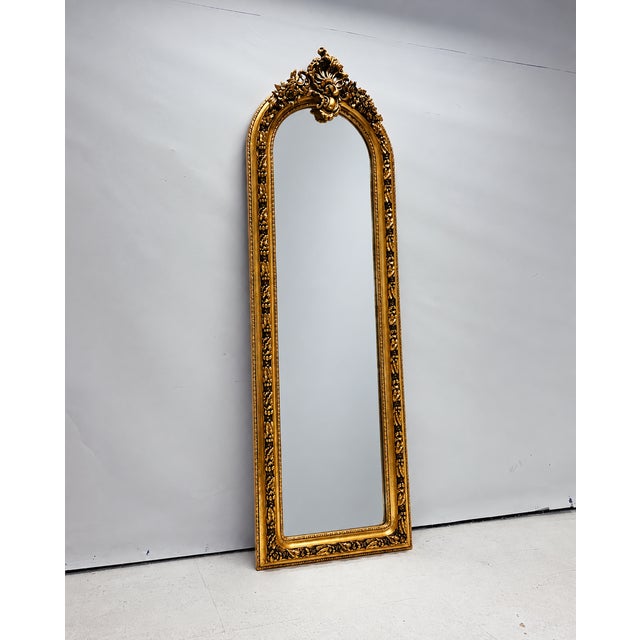 Large gold full-length mirror with ornate ornaments and a decorative crest. Thanks to its long, slender format, this...
