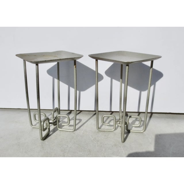 Four-legged stands with square modern Greek key turns. Molded aluminum frames. Topped by square trays with raised rims....