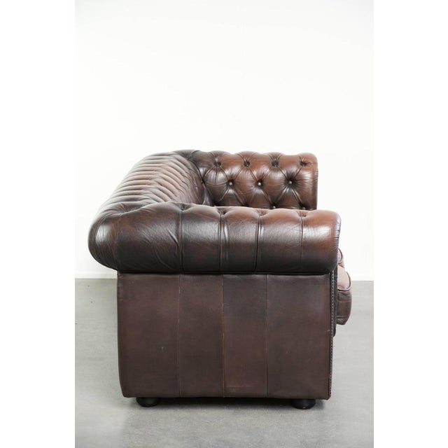 This brown English-style cowhide Chesterfield 3-seater sofa features beautiful details and is finished with loose seat...