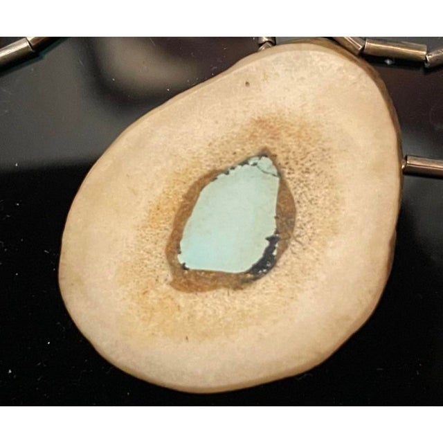 This necklace features a natural bone pendant inlaid with a very clean robins egg blue turquoise stone, suspended on a...