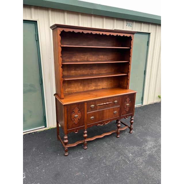 An Early American stylized two-piece hutch bookcase. Featuring a beautifully scalloped undercarriage with turned legs,...