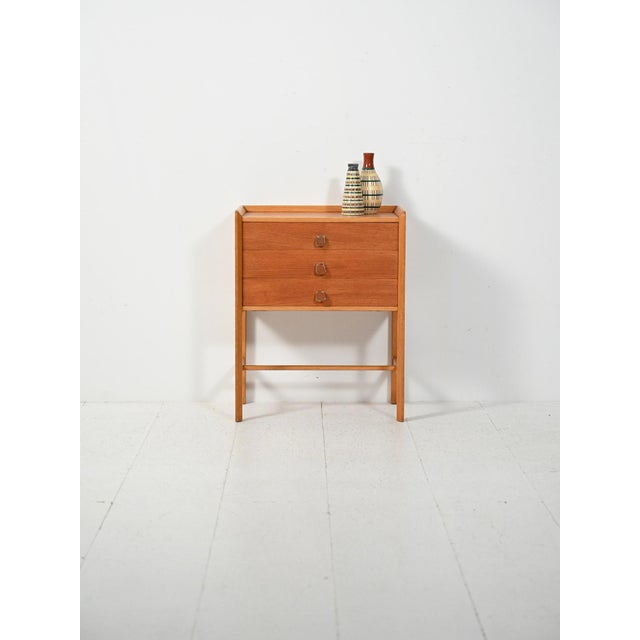 Scandinavian 1960s bedside table with oak frame and three teak drawers, characterized by clean lines and sleek proportions...