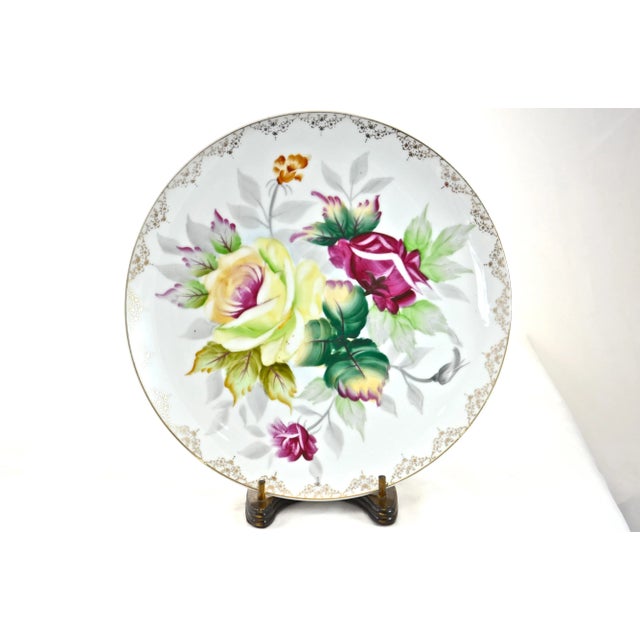 Intricately hand-painted floral porcelain plate with rose flowers in ruby red, deep green, vibrant yellow, and gold gilt....