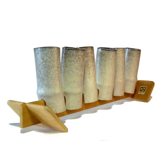 This set of six cups in extruded white-greyish-colored majolica stained with rust was placed on a wooden base. Each cup is...