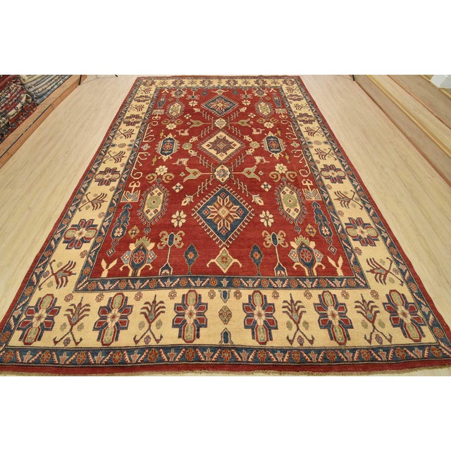 A tribal Caucasian Kazak rug hand-knotted with fine wool on a cotton foundation. This area rug features geometric...